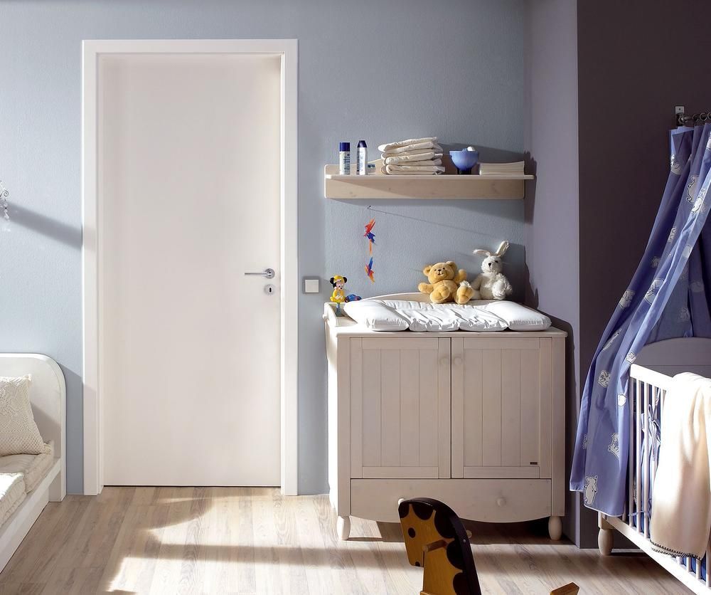 Weiße Tür in einem Kinderzimmer mit hellblauen Wänden, einem Wickeltisch, einem Kinderbett und einem Schaukelpferd.