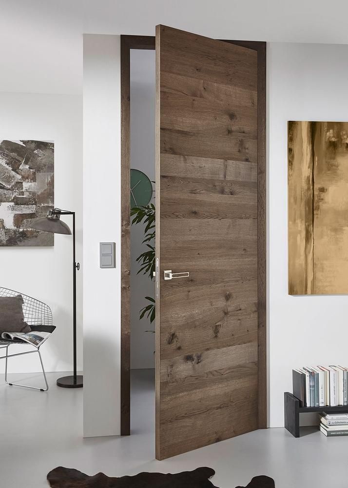 Offene Holztür in einem weiß getünchten Raum mit Kunstwerken und minimalistischen Möbeln.