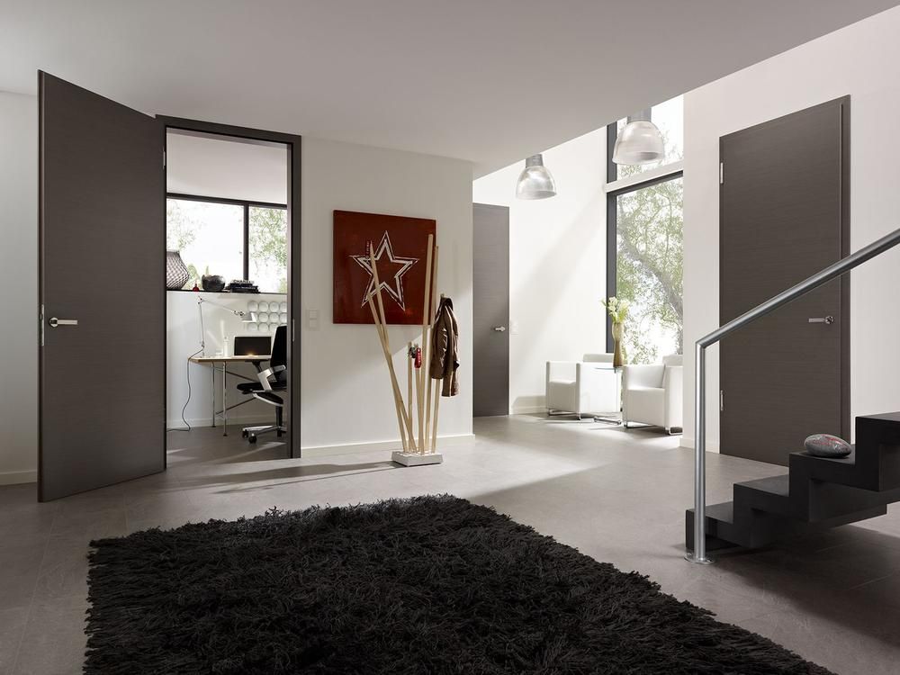 Interieur mit grauen Türen, einem dunklen Teppich, einem Heimbüro und einem Treppenhaus.