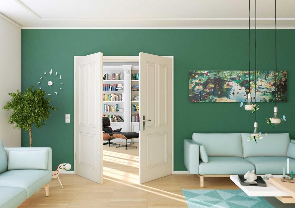 Wohnzimmer mit grünen Wänden, blauen Sofas und einer Tür, die zu einem Zimmer mit einem Bücherregal führt.