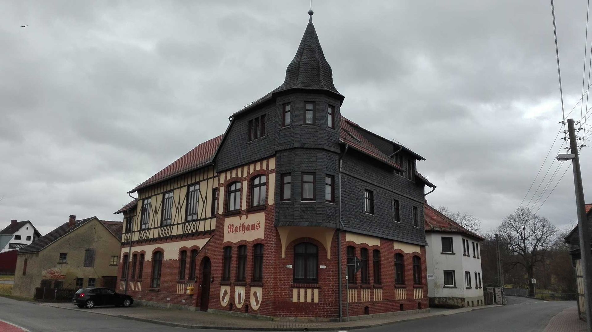An einer Straßenecke steht ein großes Gebäude mit einem Turm darauf.