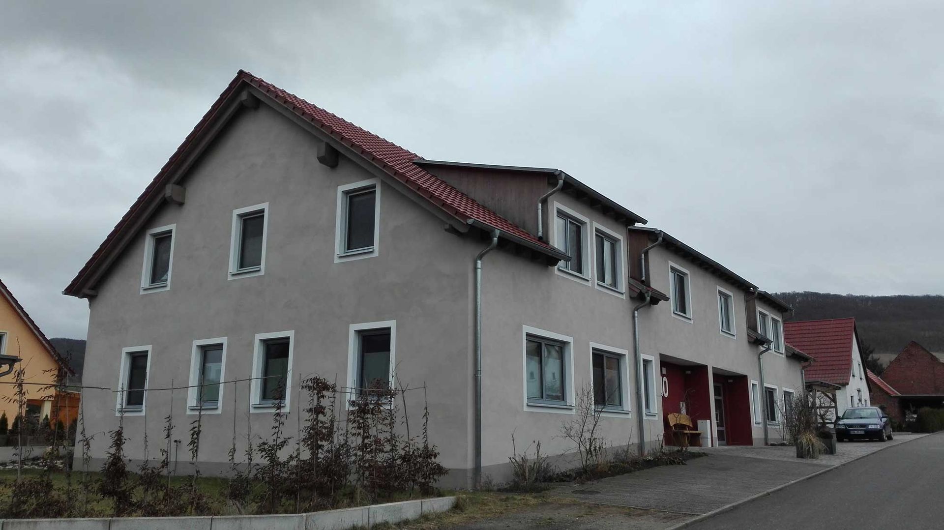 Ein großes Haus mit einem roten Dach steht am Straßenrand.
