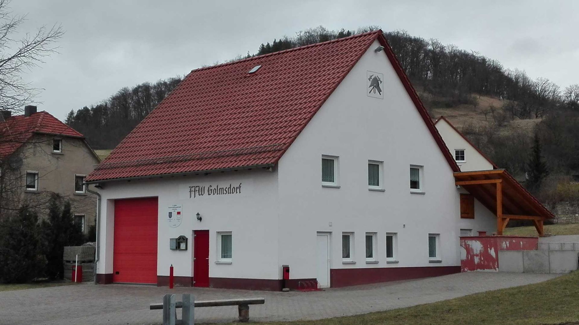 Ein weißes Haus mit einem roten Dach und einer roten Tür