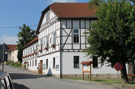 Am Straßenrand steht ein weißes Gebäude mit rotem Dach.