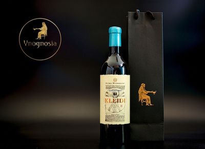 Flasche mit türkisfarbenem Verschluss und schwarzer Geschenktüte vor dunklem Hintergrund, mit Vignosia-Logo.