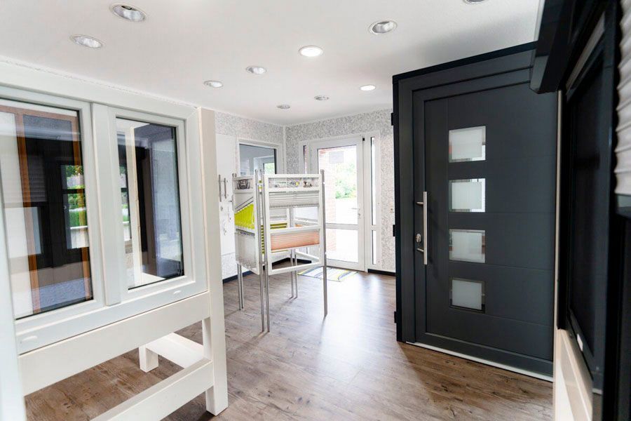 Ein Raum mit einer schwarzen Tür und vielen Fenstern.