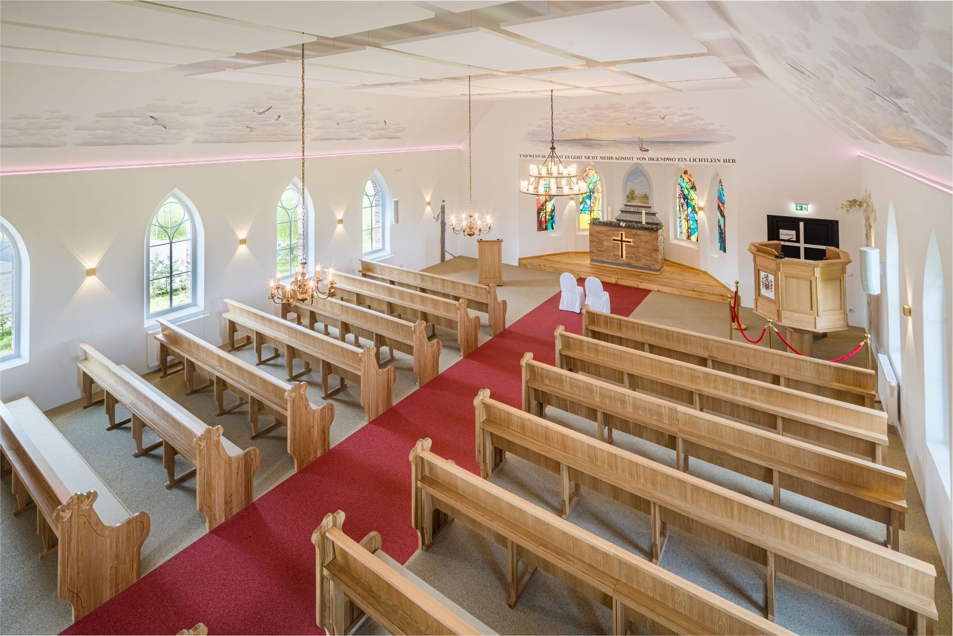 Das Innere einer Kirche mit Holzbänken und einem roten Teppich.