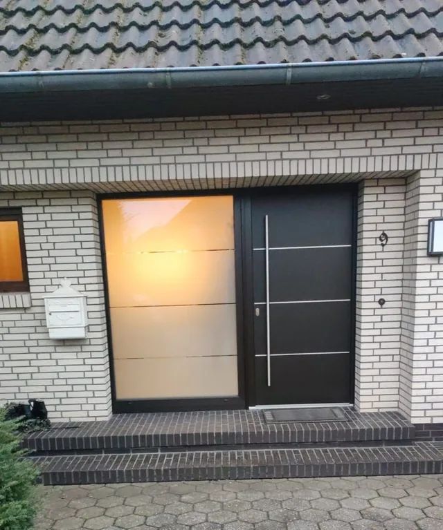 Ein weißes Backsteinhaus mit einer schwarzen Tür und Stufen