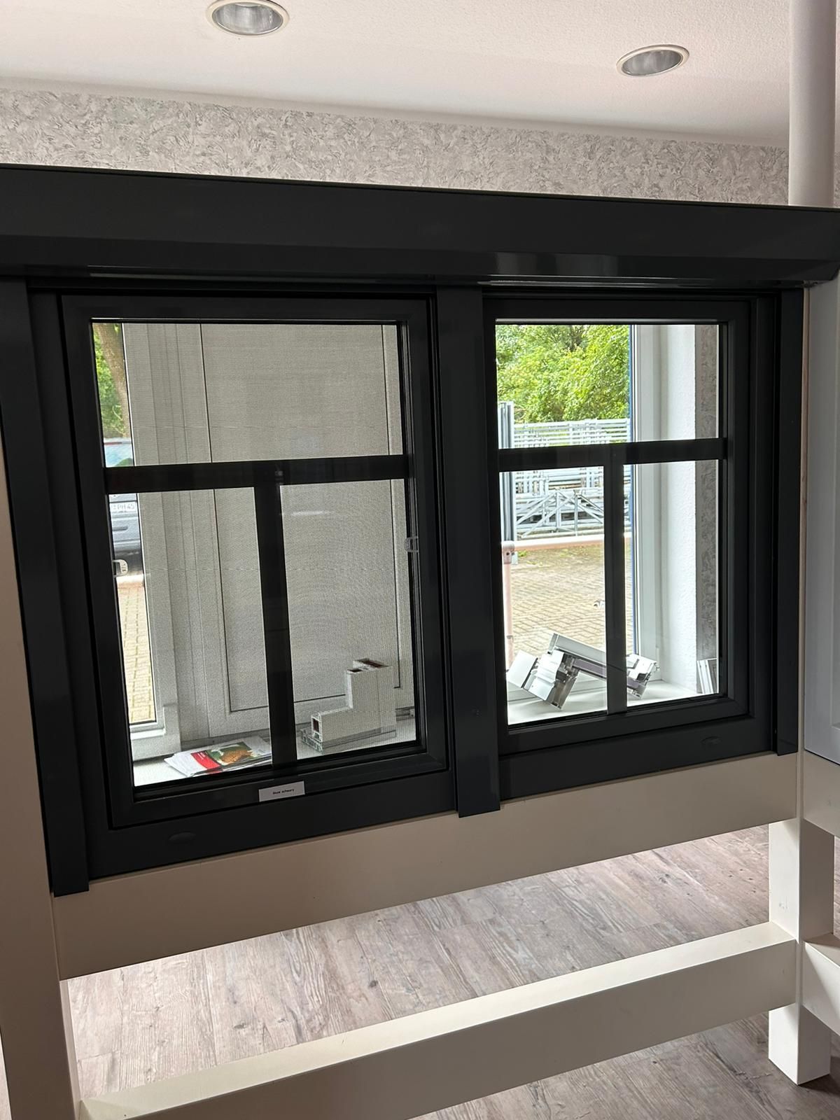 Eine Nahaufnahme eines Fensters mit einem schwarzen Rahmen in einem Raum.