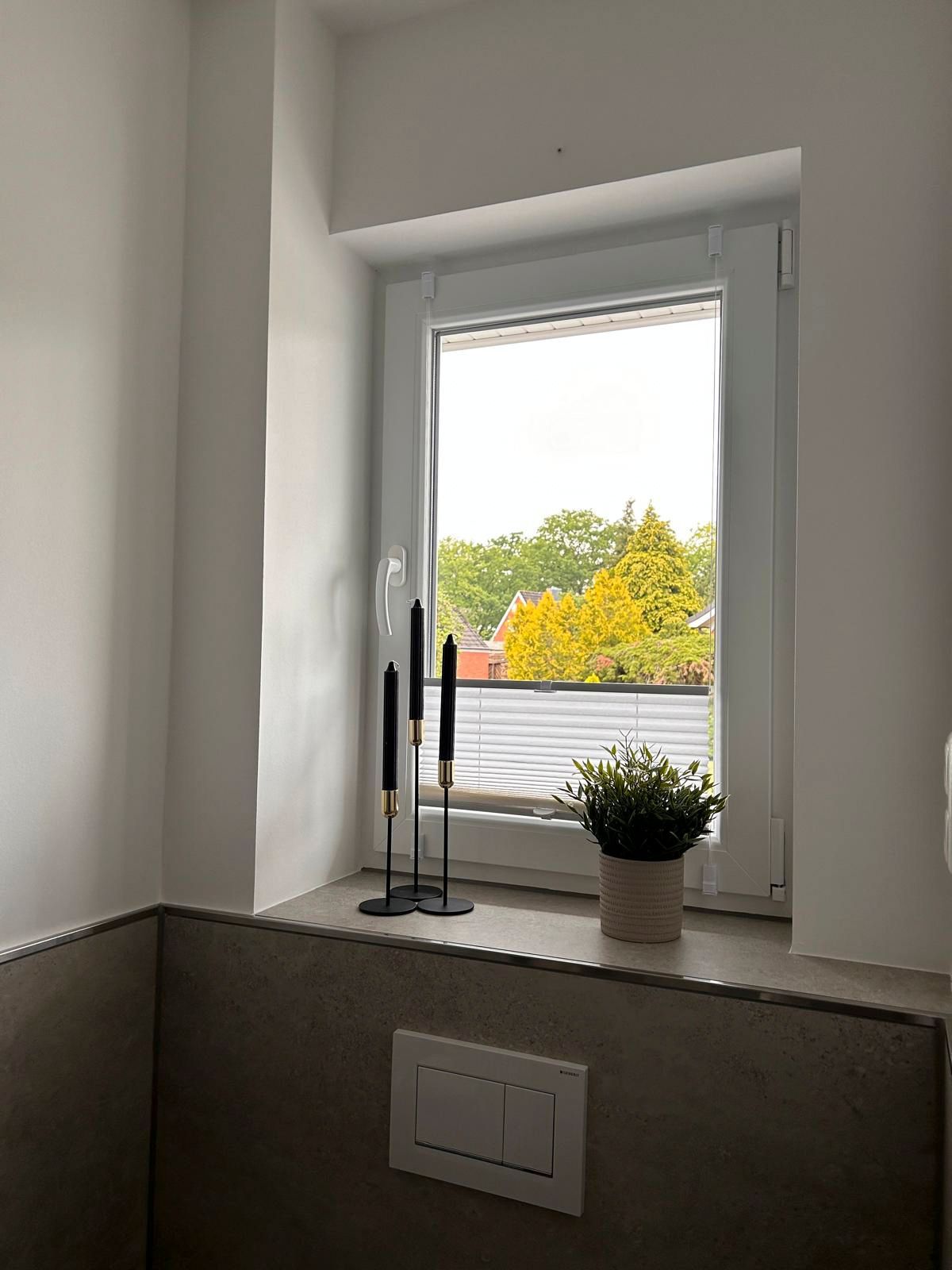 Ein Badezimmer mit Fenster und Kerzen auf der Fensterbank.