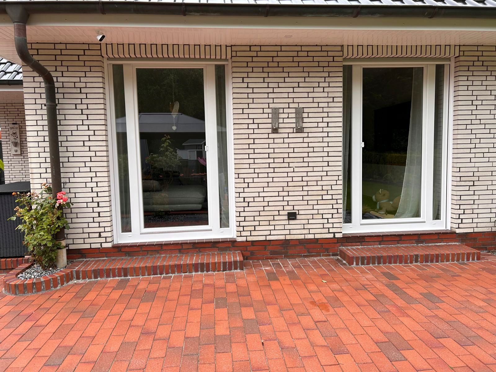 Ein weißes Backsteinhaus mit einer roten Backsteinterrasse davor