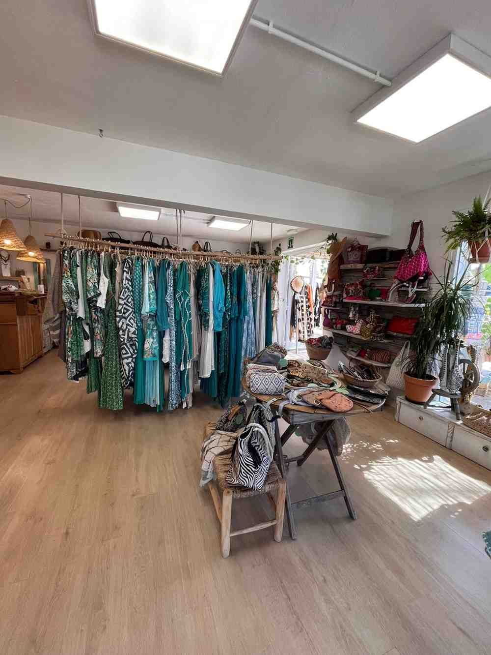 Tienda de ropa boutique con vestidos coloridos, estanterías y un suelo de madera brillante.