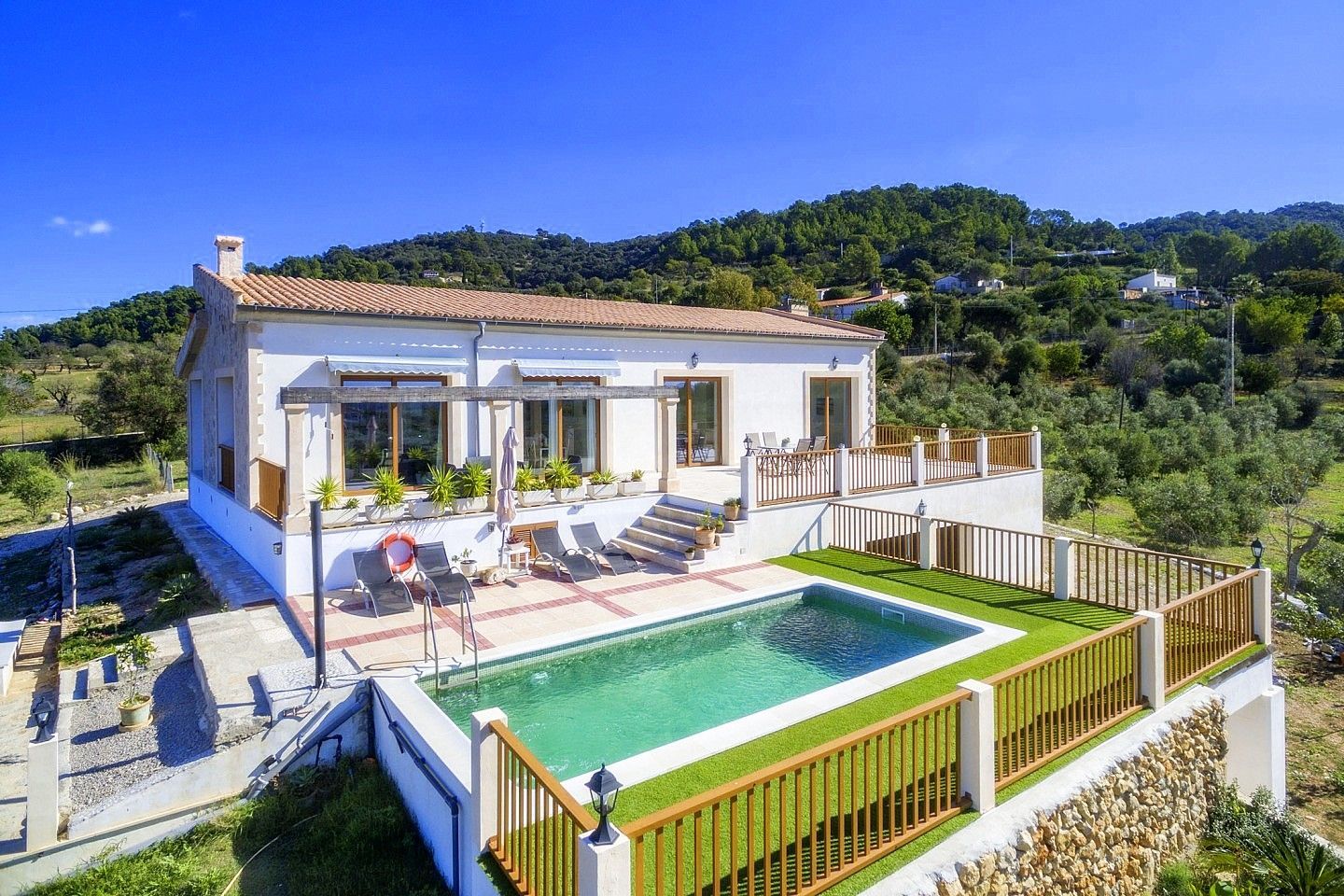 Modern white house with patio, pool, and mountain views under a clear blue sky