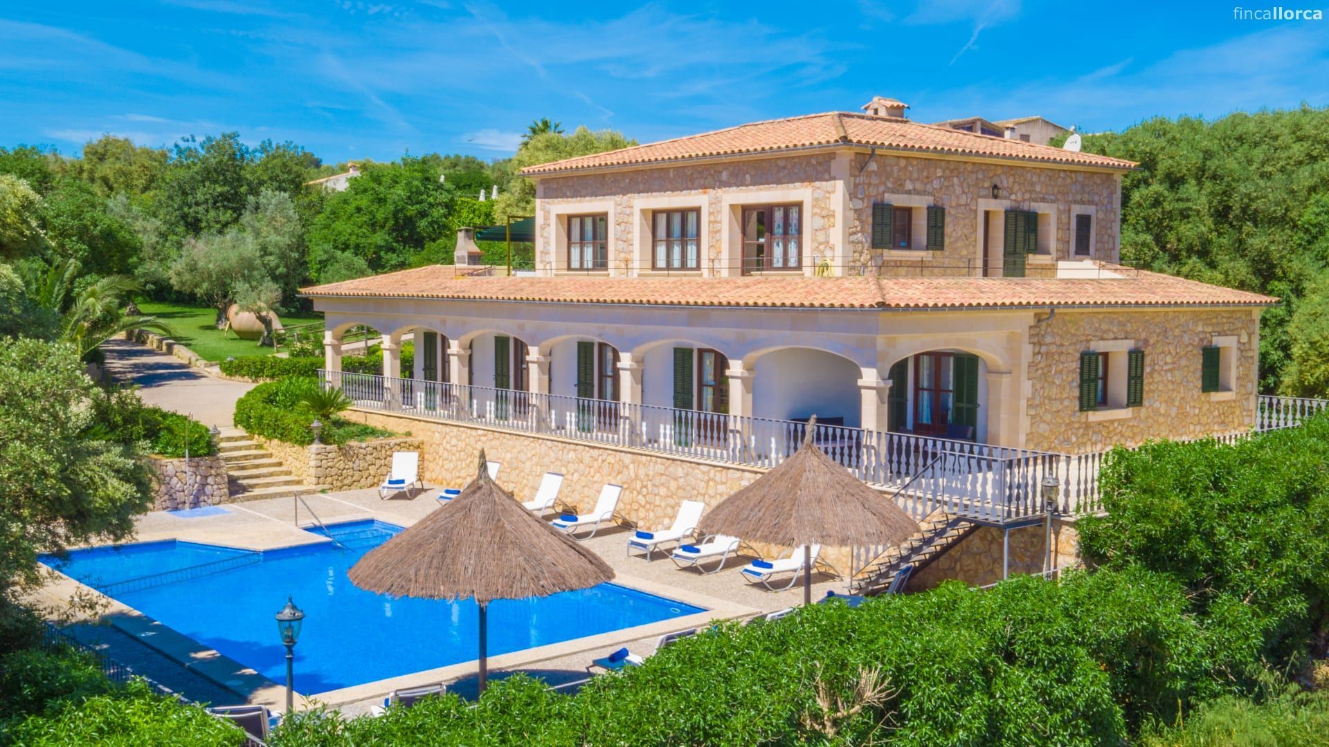 Luxurious villa with pool, sun loungers, and ocean view surrounded by lush greenery