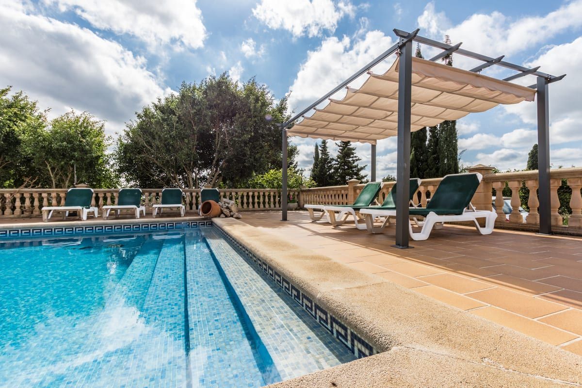 A swimming pool with a pergola and chairs around it