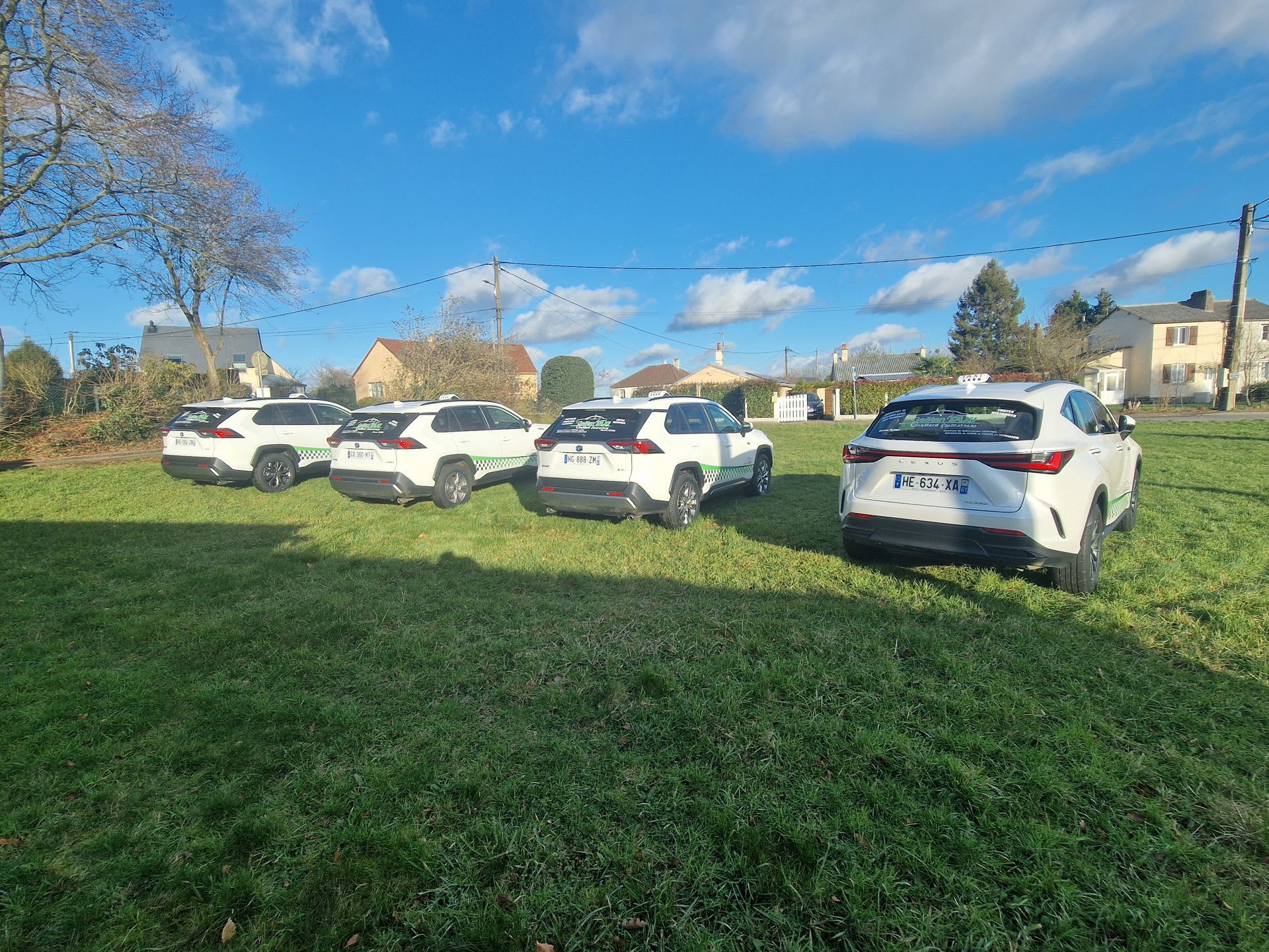 Quatre SUV garés en rang sur une pelouse sous un ciel légèrement nuageux.