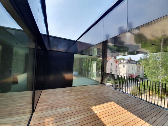 Moderne Terrasse mit schwarzen Akzenten und Glaswänden, mit Blick auf die Stadt.