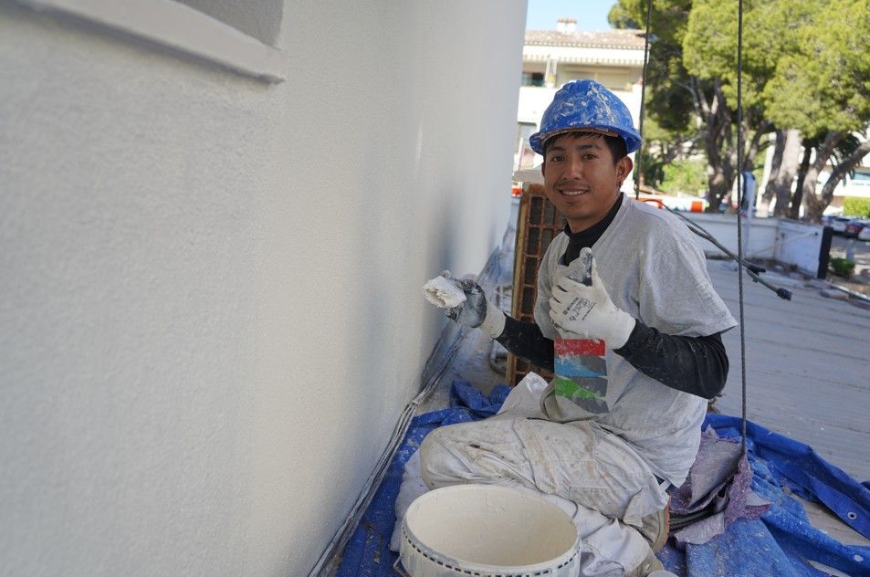 Operario aplicando detalles de pintura en fachada rehabilitada