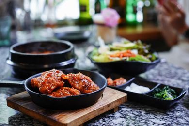 A bowl of food is sitting on a wooden cutting board on a table.