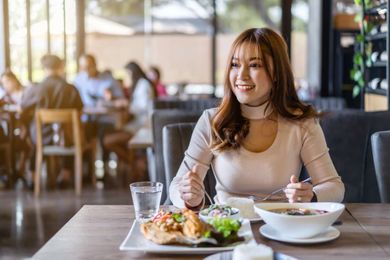 A woman is sitting at a table in a restaurant eating food.