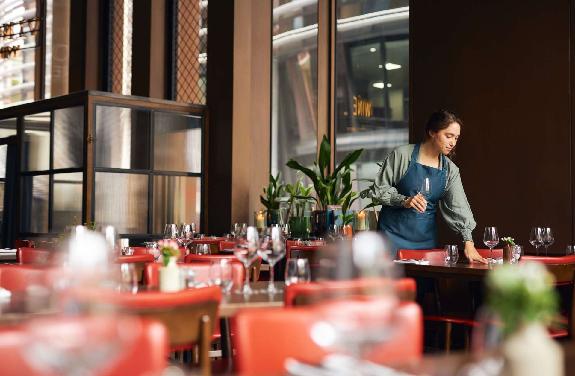 A woman is standing at a table in a restaurant.