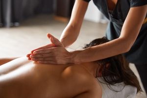 Persona recibiendo un masaje de espalda en una camilla en un entorno tipo spa.