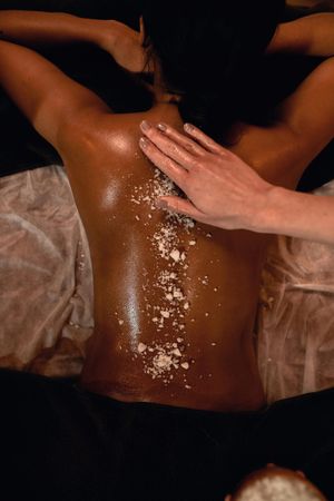 Masaje de espalda con aceite a una persona tumbada boca abajo sobre una mesa cubierta con una toalla.