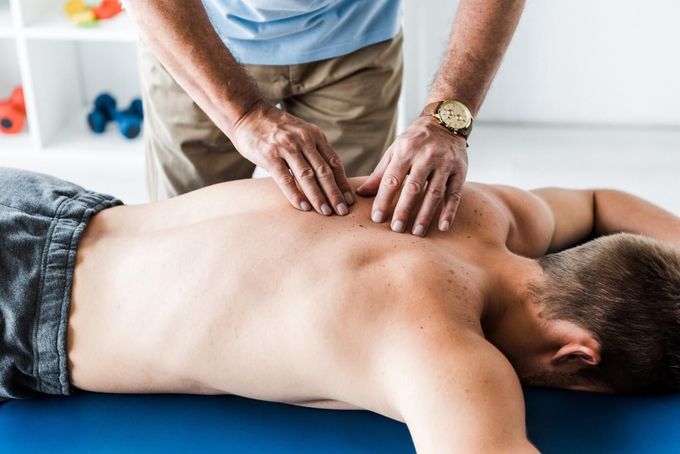 Hombre recibiendo masaje de espalda de otra persona en una clínica; manos en la espalda.