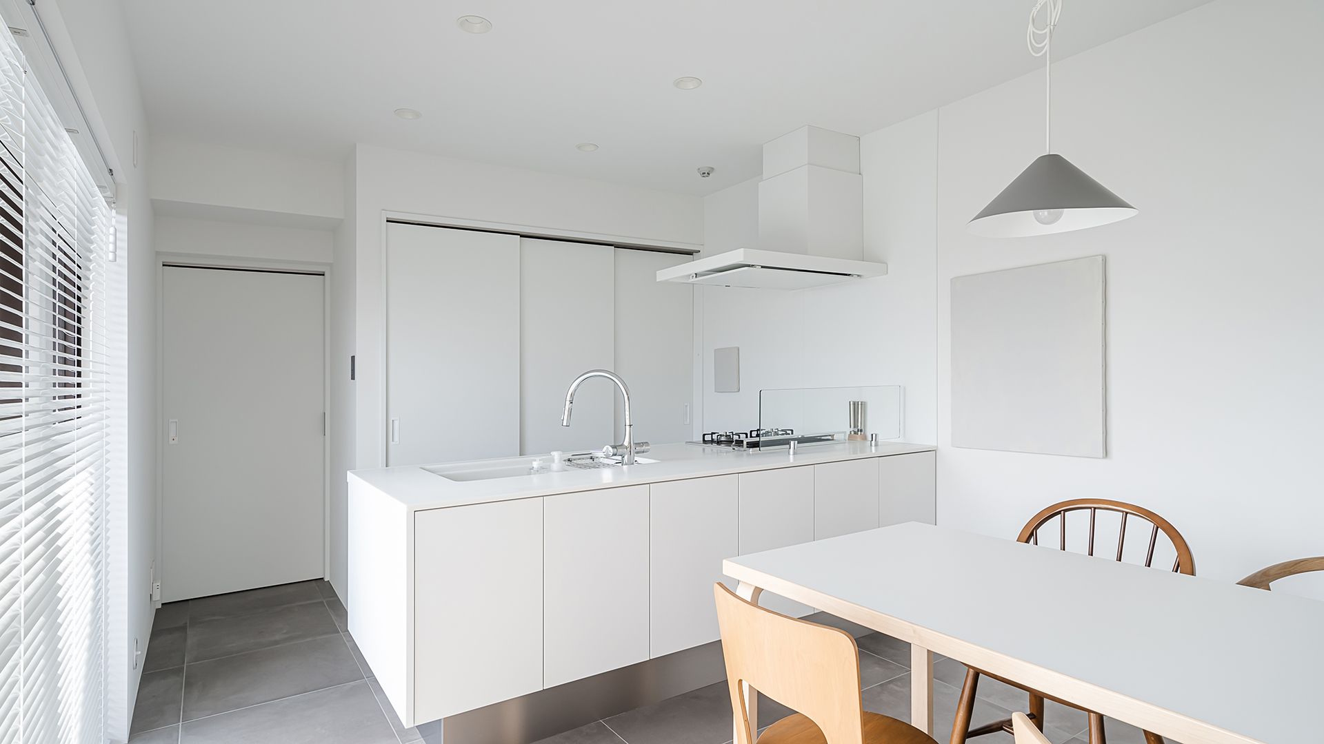 Una cocina con muebles blancos, una mesa y sillas.
