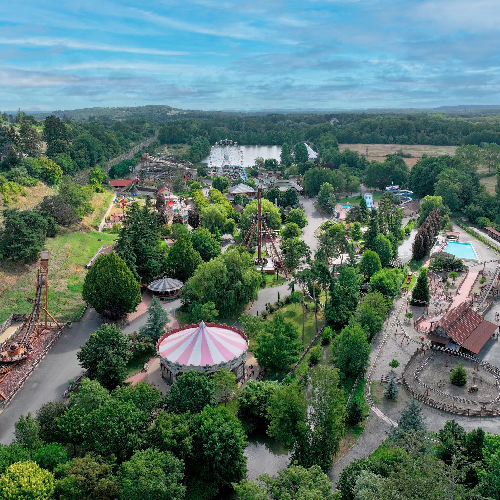 Vue aérienne d'un parc d'attractions luxuriant avec des manèges.