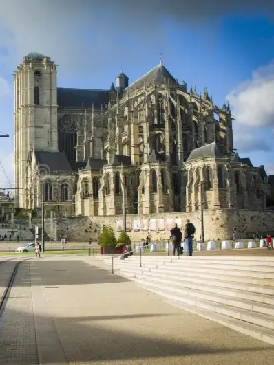 Cathédrale gothique aux hautes tours de pierre et aux arcs-boutants.