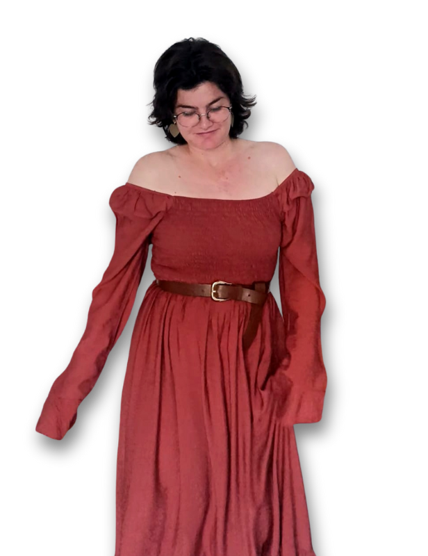 Una mujer con un top blanco y jeans azules está parada en una habitación.