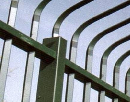 Un primer plano de una valla metálica verde con un cielo azul de fondo.