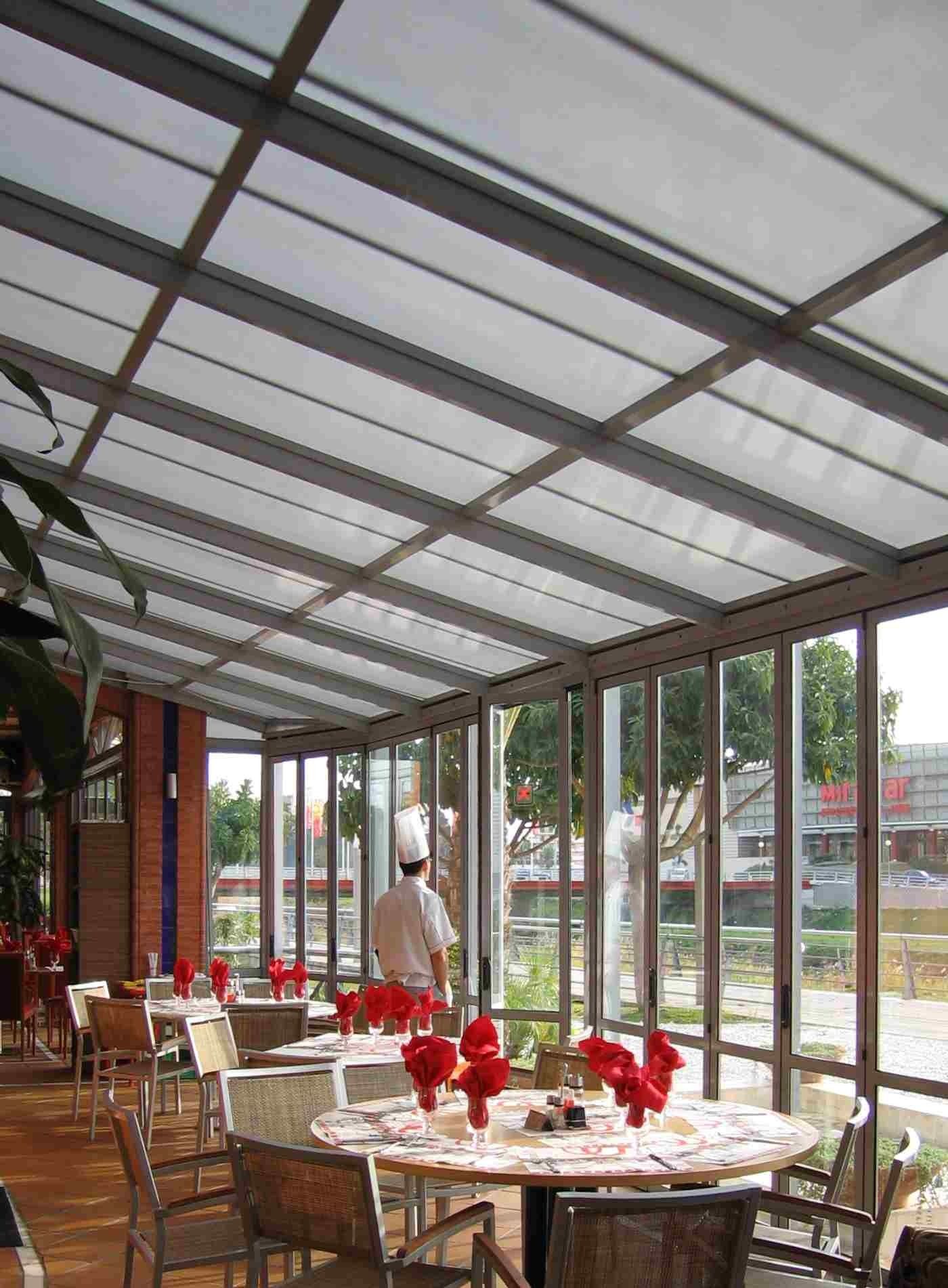 Un restaurante con mesas y sillas y un chef al fondo.