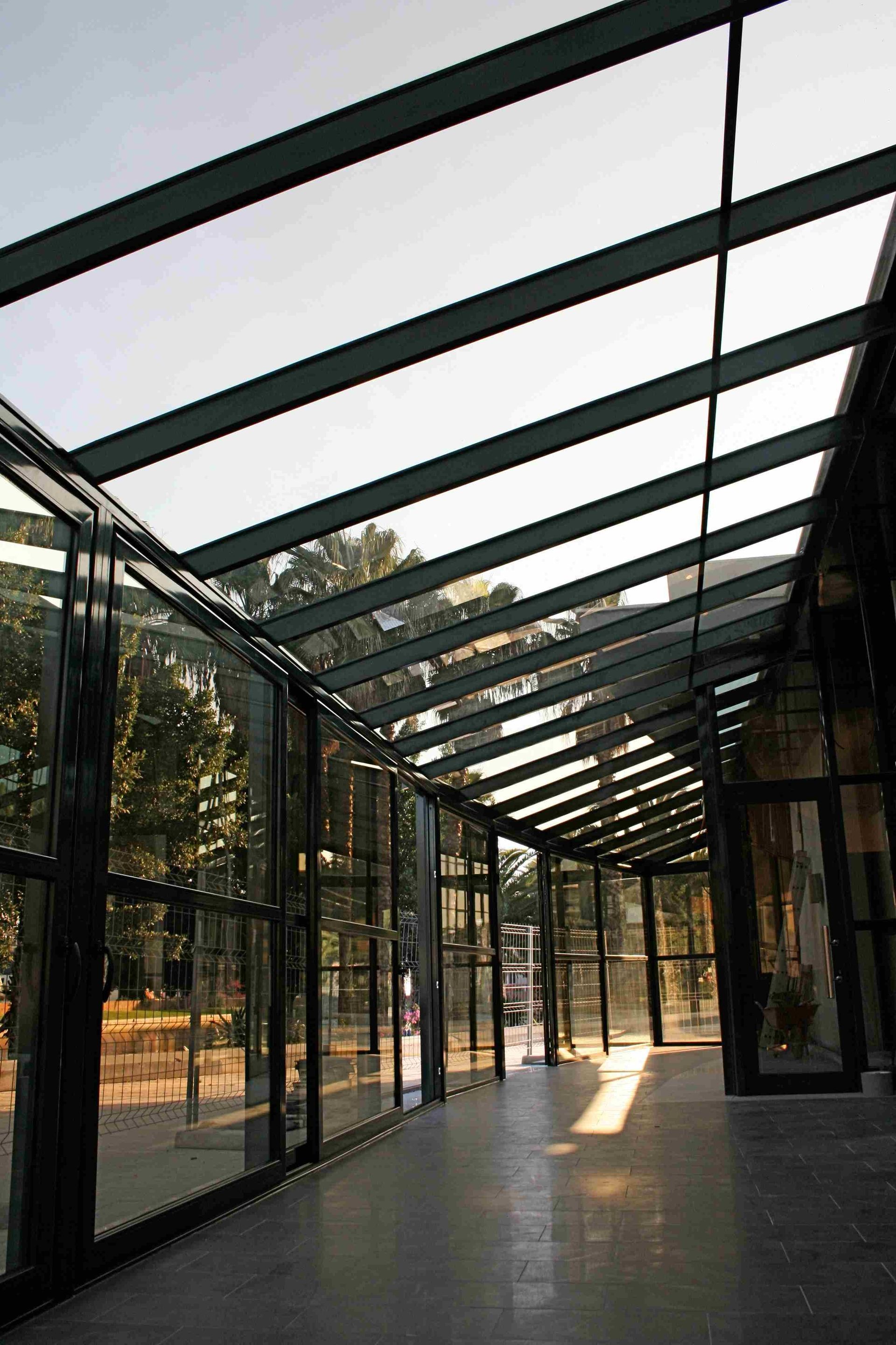 Un largo pasillo con techo de cristal y muchas ventanas.