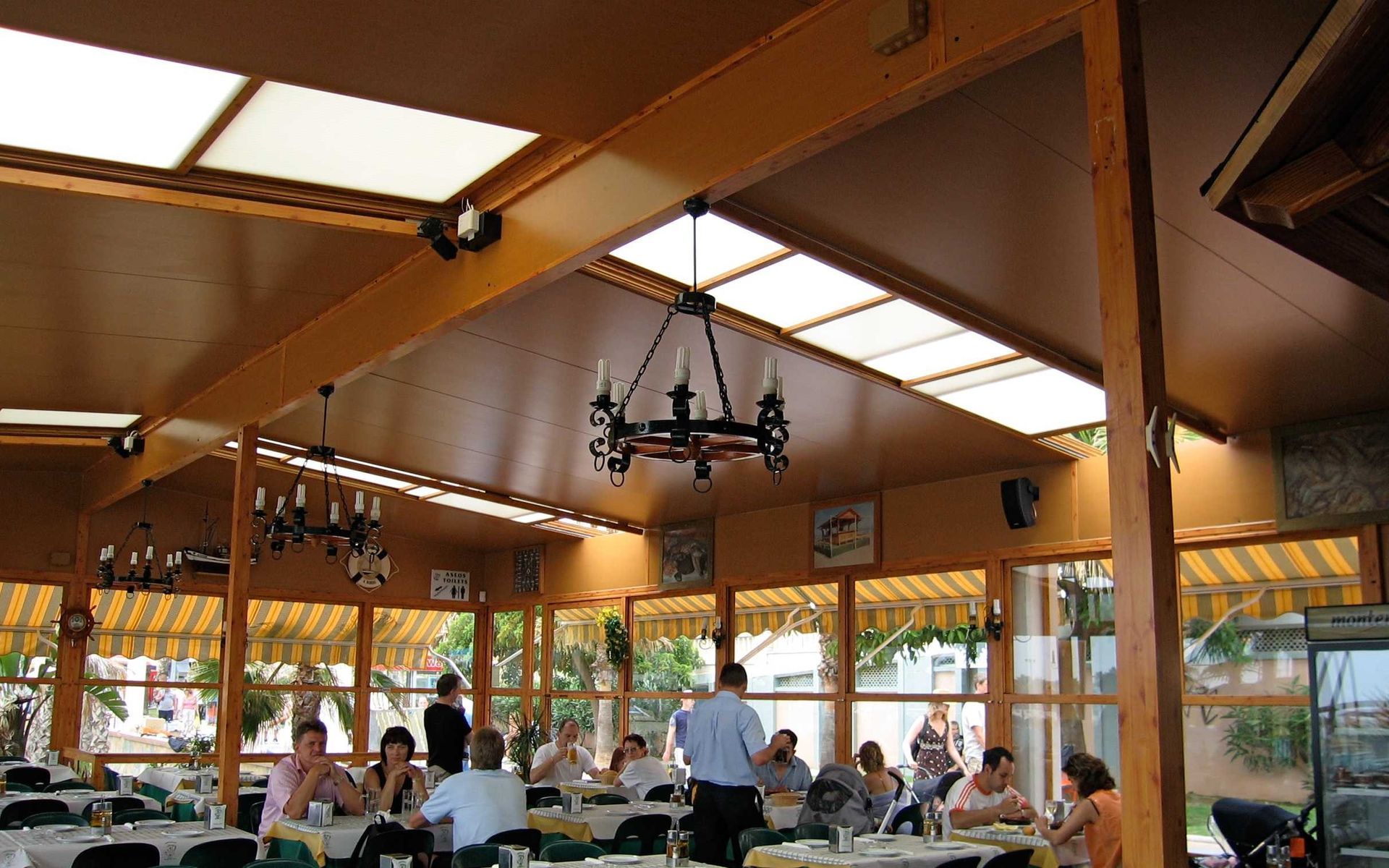 Un restaurante con gente sentada en mesas y una lámpara de araña colgando del techo.