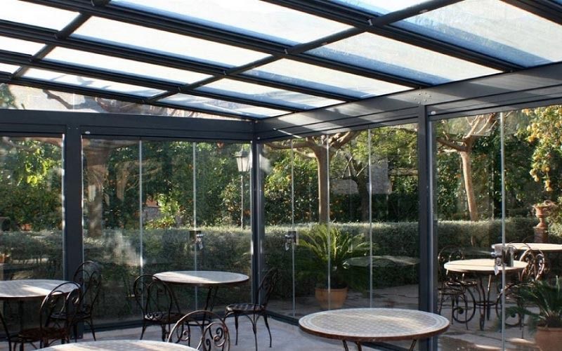 Una habitación con mesas y sillas bajo un techo de cristal.