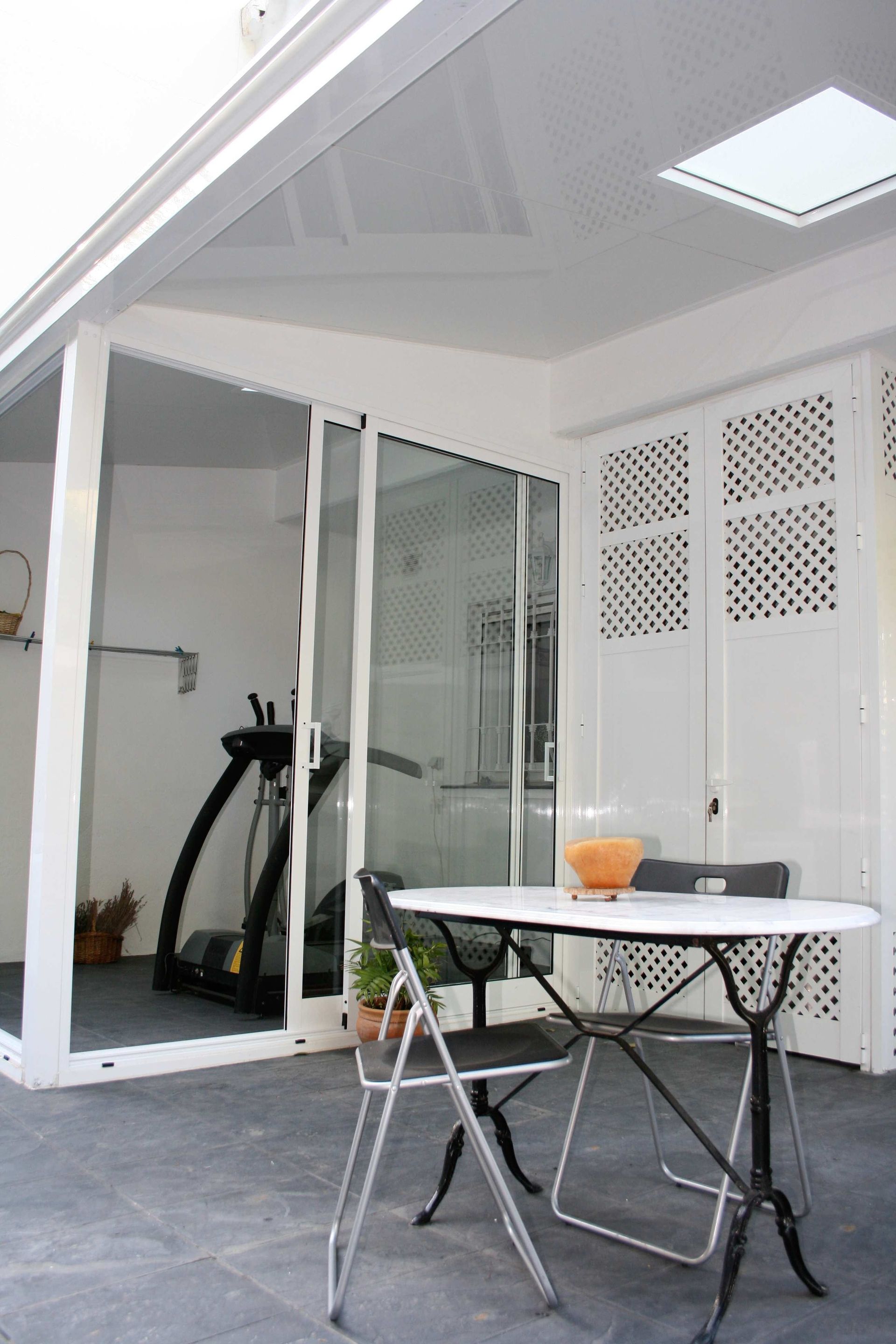 Un patio con una mesa y sillas y una cinta de correr al fondo.