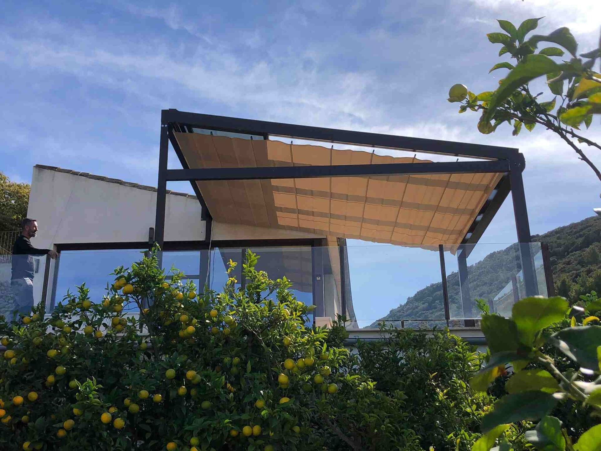 Una pérgola está situada en la parte superior de un edificio al lado de un árbol.