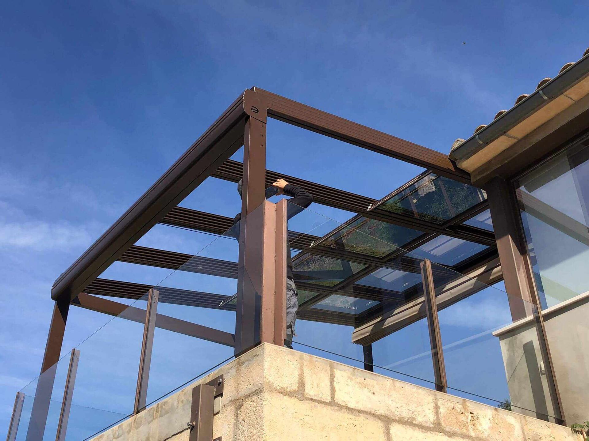 Una pérgola con techo de cristal se encuentra encima de un edificio de ladrillo.