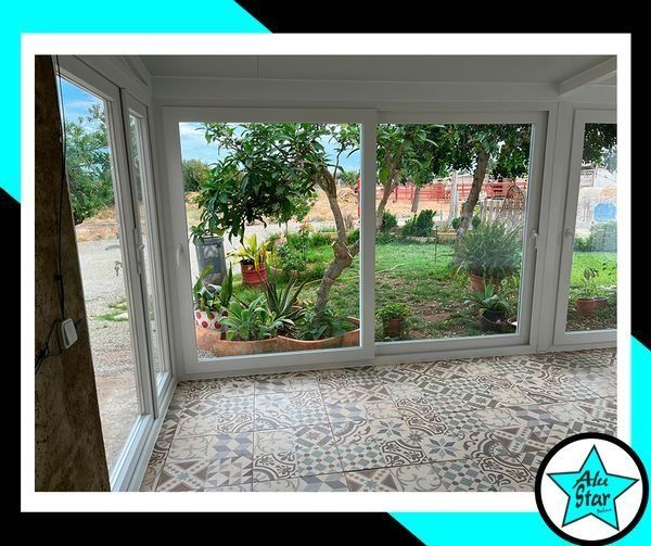 Una habitación con muchas ventanas que dan a un jardín.