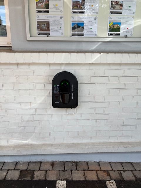 Une femme charge sa voiture électrique à une borne de recharge.