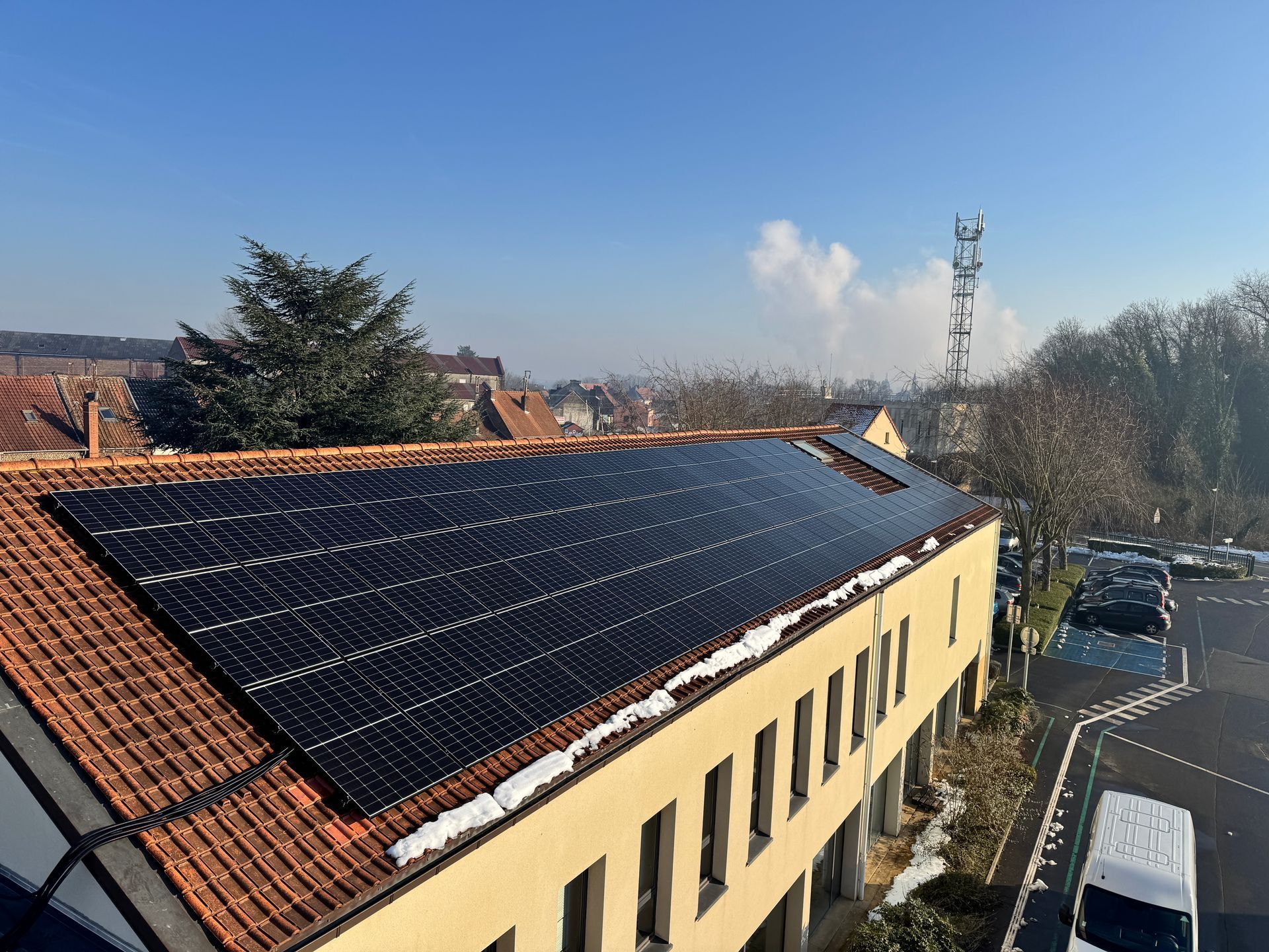 Une rangée de panneaux solaires posée au sommet d'une colline entourée d'arbres.