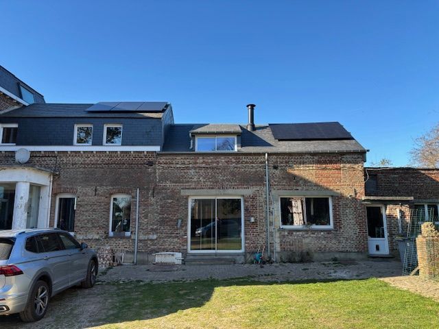 Une rangée de panneaux solaires posée au sommet d'une colline entourée d'arbres.