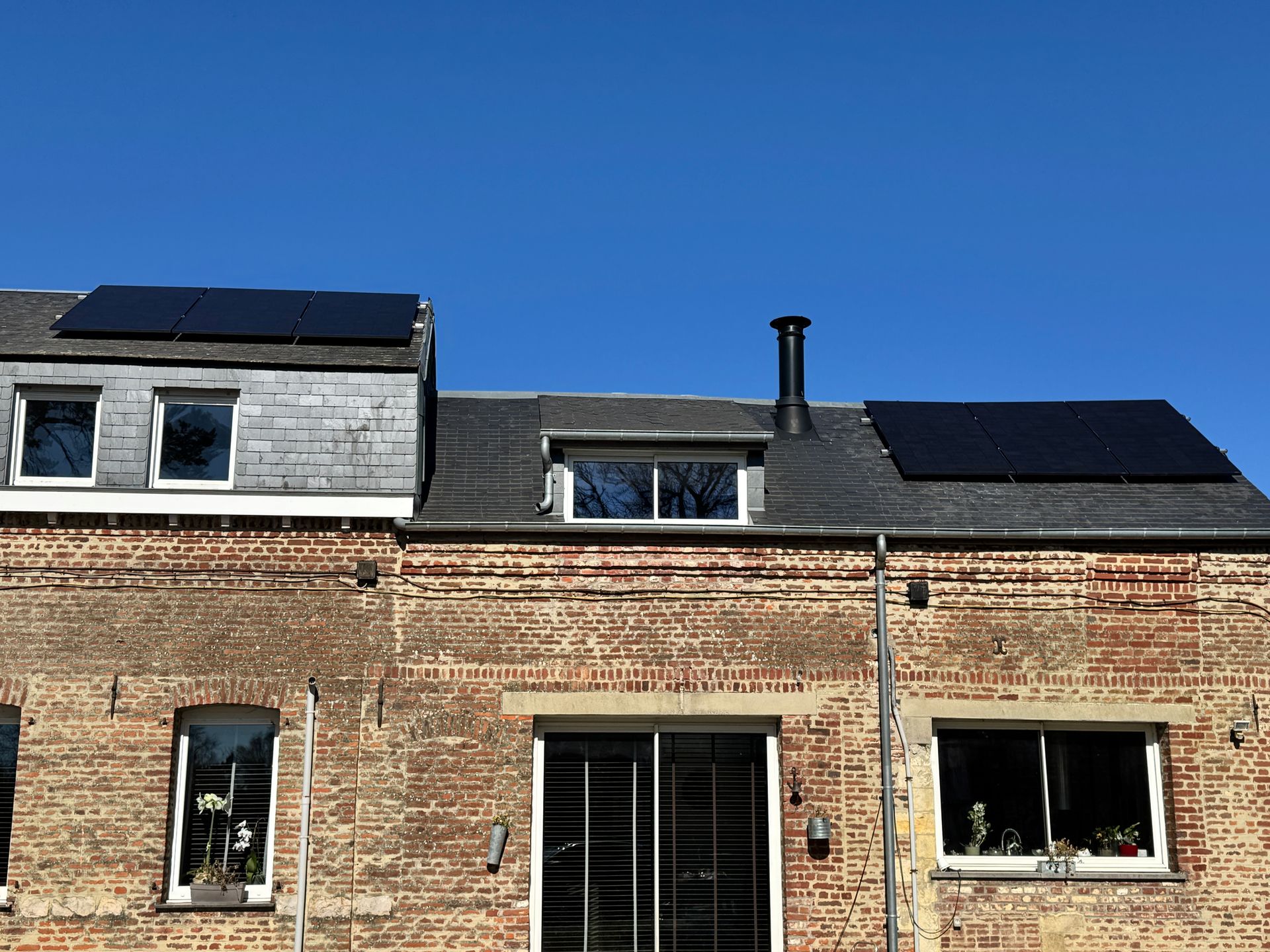 Deux hommes installent des panneaux solaires sur le toit d'une maison.
