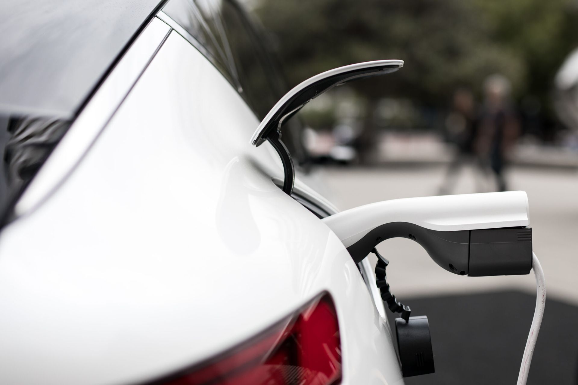 Une voiture électrique blanche est en cours de recharge dans une borne de recharge.
