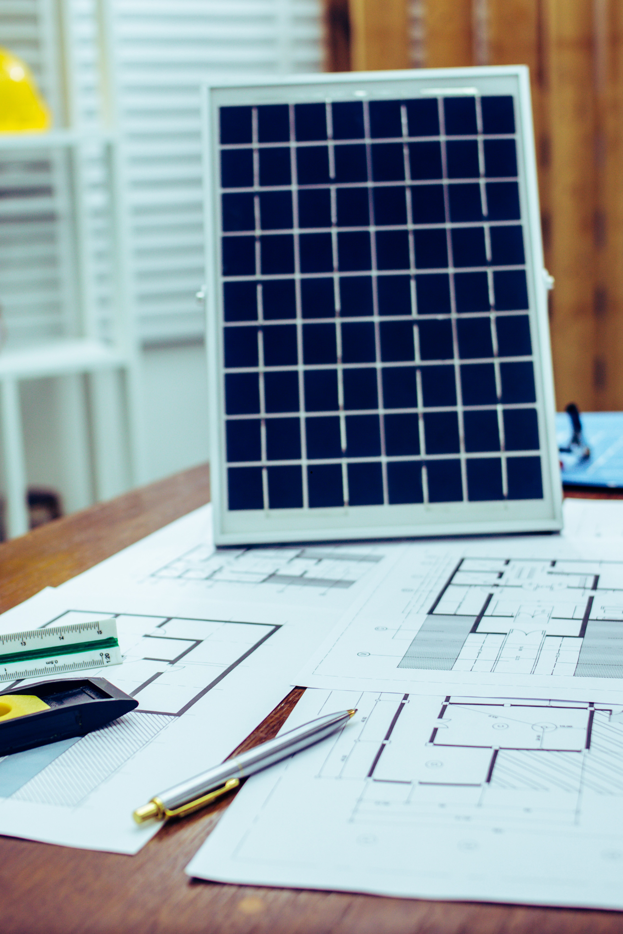 Panneau solaire sur plans avec un stylo et une règle sur une table, à l'intérieur.