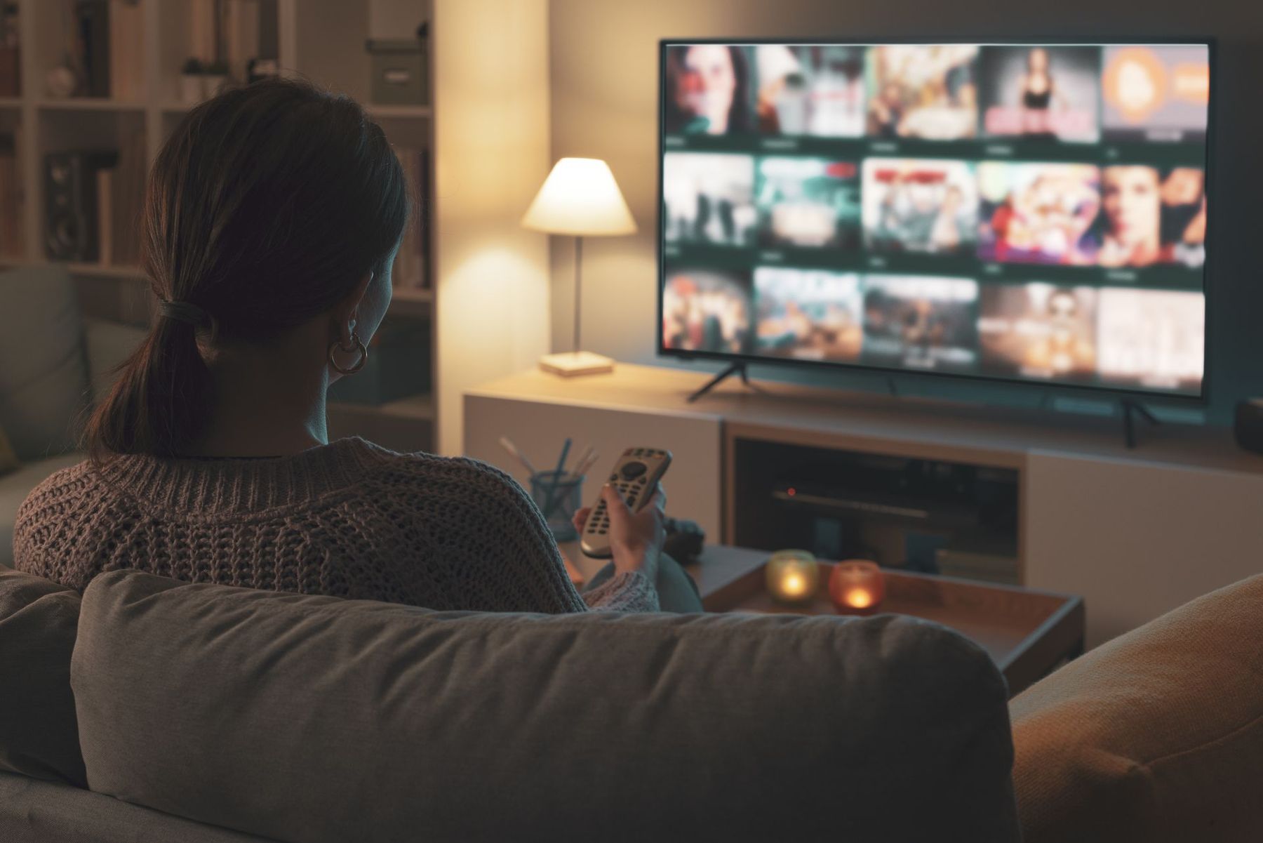 Une femme assise dans un canapé qui regarde la télévision
