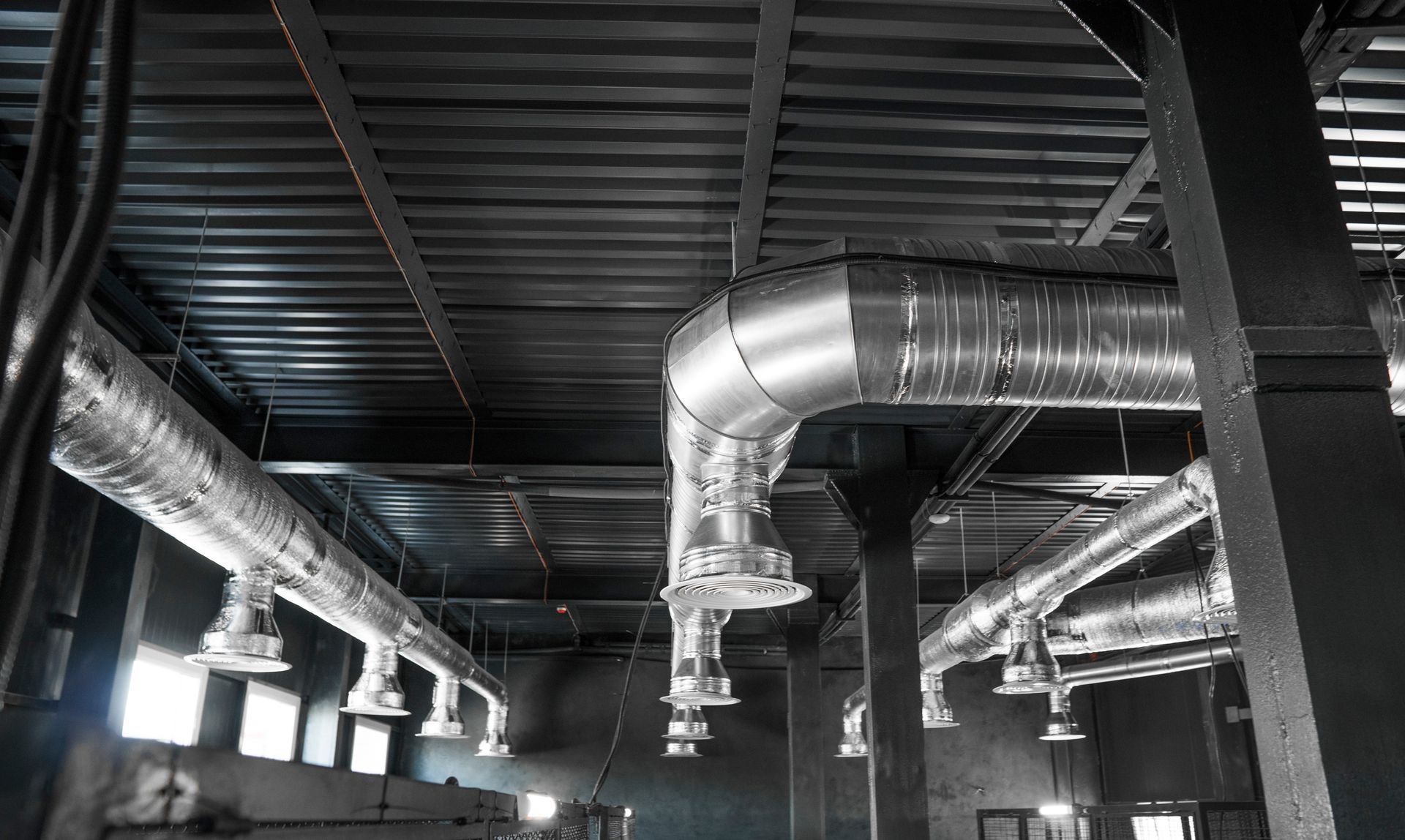 Ein Schwarzweißfoto einer Fabrik mit vielen Rohren, die von der Decke hängen.