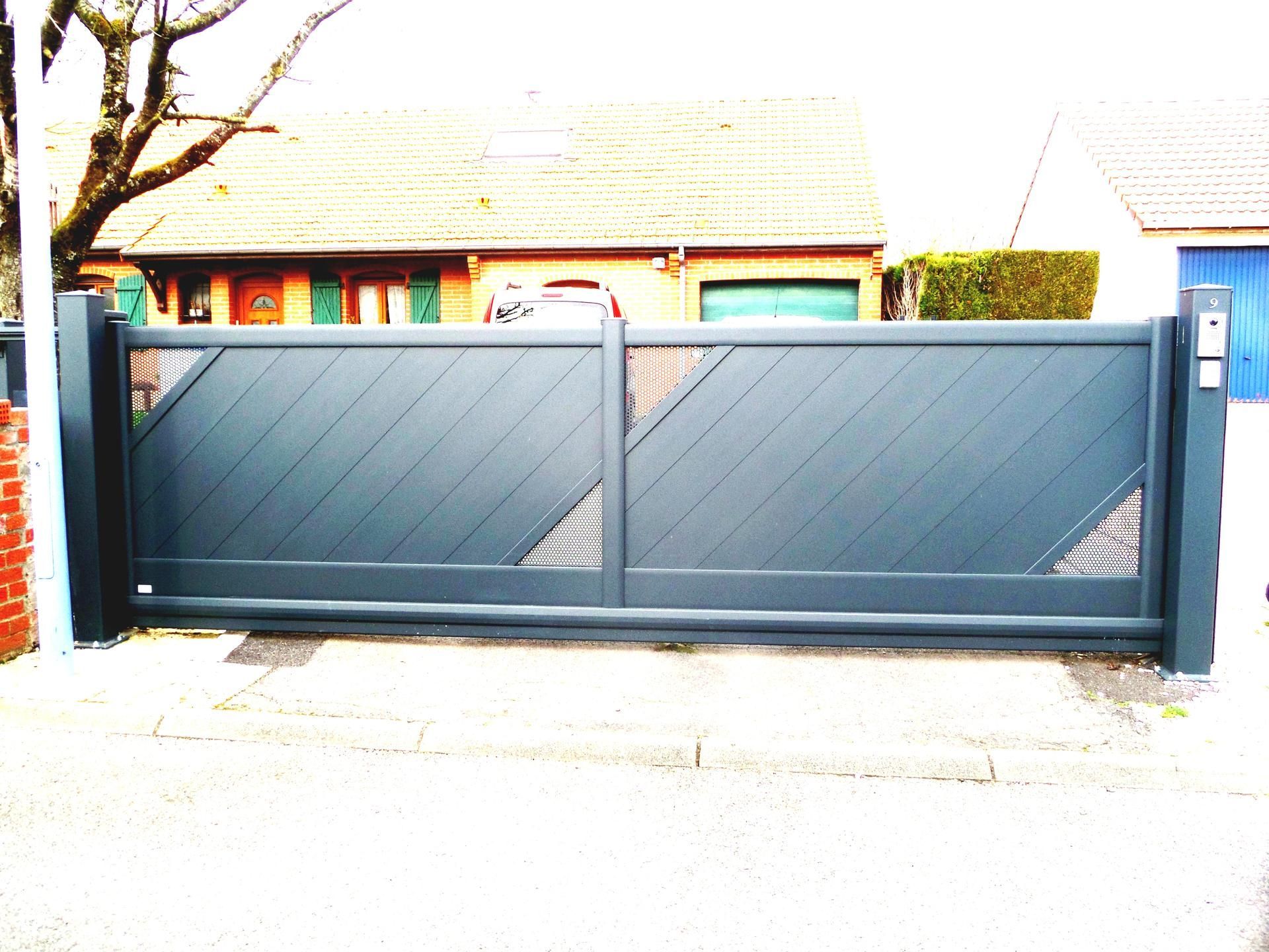 Portail coulissant en métal gris devant une maison.